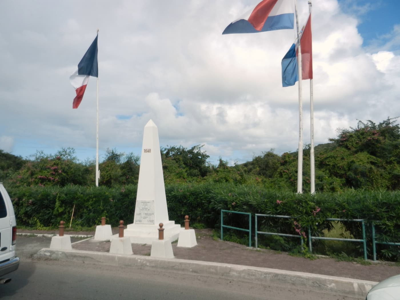 The white obelisk marking the border between the Dutch and French sides, with flags flying