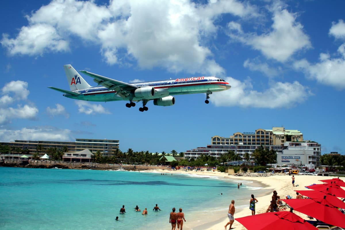 A passenger jet on final approach low over the beach and hotels at Maho